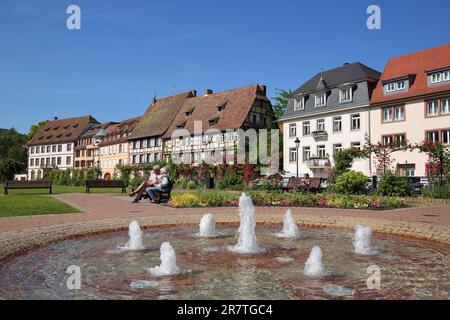 Blick auf Fachwerkhäuser am Quai Anselmann mit Brunnen und Menschen auf der Parkbank, idyllisch, Wissembourg, Weissenburg, Bas-Rhin, Elsass, Frankreich Stockfoto