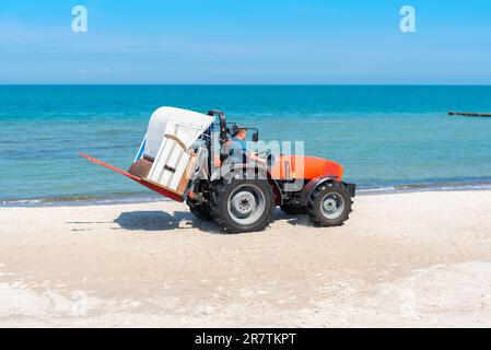 Die Liegenvermietung stellt ihre Körbe mit einem Traktor an den Stränden der Ostsee nahe Graal M auf Stockfoto