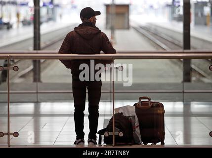 Ein Mann steht mit seinem Gepäck vor zwei leeren Bahngleisen im Hauptbahnhof Leipzig, Sachsen, Deutschland Stockfoto