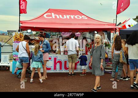 Farbenfroher Churros-Stand auf dem Pop-up-Straßenmarkt und Food Festival an der Strandpromenade von Morecambe in Lancashire. Stockfoto