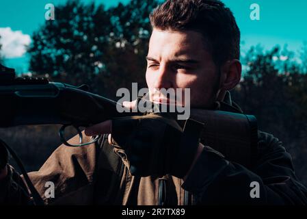 Scharfschützen aus nächster Nähe bei der Jagd im Freien. Nahaufnahme Porträt von Hamdsome Hunter. Jäger mit Schrotflinte auf der Jagd Stockfoto