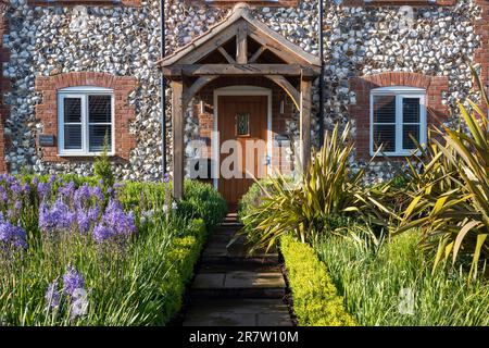 Traditionelles hübsches Backstein- und Feuersteinhaus mit Veranda, Studentenfenstern, Vordergarten und Pfad im malerischen Dorf Great Massingham in Norfolk, England Stockfoto