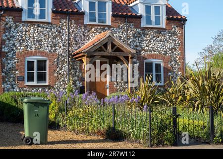 Traditionelles hübsches Backstein- und Feuersteinhaus mit Veranda, Studentenfenstern, Vordergarten und Pfad im malerischen Dorf Great Massingham in Norfolk, England Stockfoto