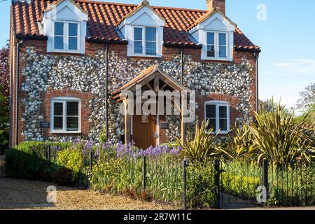 Traditionelles hübsches Backstein- und Feuersteinhaus mit Veranda, Studentenfenstern, Vordergarten und Pfad im malerischen Dorf Great Massingham in Norfolk, England Stockfoto