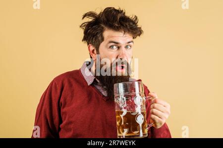 Ein bärtiger Mann beim oktoberfest trinkt Bier. Überraschter bärtiger Mann mit Craft-Bier. Ein gutaussehender Mann, der frisch gezapftes Bier trinkt. Trunkenheitsverkostung Stockfoto