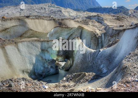 Der Gletscher schmilzt, weil er mit einer Staubschicht bedeckt ist, die ihn in der Sonne aufheizt. Stockfoto