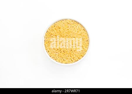 Risoni- oder Orzo-Reispasta in weißer Keramikschüssel auf weißem Hintergrund. Italienische Küche. Hartweizengrieß-Pasta für Risotto und Salate Stockfoto