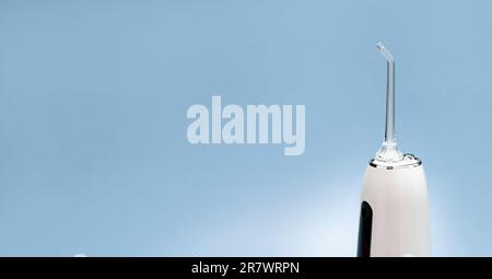 Banner einer Munddusche, Zahnwasser-Zahnreiniger, weiße, tragbare, wiederaufladbare Zahnseide auf blauem Hintergrund. Wasserdicht Stockfoto