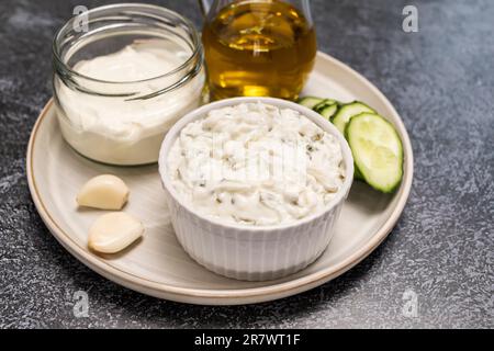 Tzatziki mit traditioneller griechischer Joghurt-Sauce, Dressing in weißer Schüssel, aus geriebenem Gurken, Sauerrahm-Joghurt, Olivenöl, Knoblauch, Kräutern mit Stockfoto