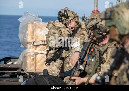 230613-N-LK647-1570 ATLANTISCHER OZEAN (13. Juni 2023 13) Seeleute, die der Sprengstoffbeseitigungsmobileinheit 6 zugeteilt sind, behalten die Sicherheit auf dem Cockpit des geführten Raketenkreuzers der Ticonderoga-Klasse USS Normandy (CG 60) bei, während sie eine HVBSS-Übung (Helicopter Visit, Board, Search, and seizure) durchführen. Juni 2023. Normandy ist Teil der Gerald R. Ford Carrier Strike Group und befindet sich in einem geplanten Einsatz in den USA Marinestreitkräfte Europa Einsatzgebiet, angestellt von der Sechsten Flotte, um die Interessen der USA, Verbündeten und Partner zu verteidigen. (USA Marinefoto von Mass Communication Specialist 2. Class Malachi Lake Stockfoto