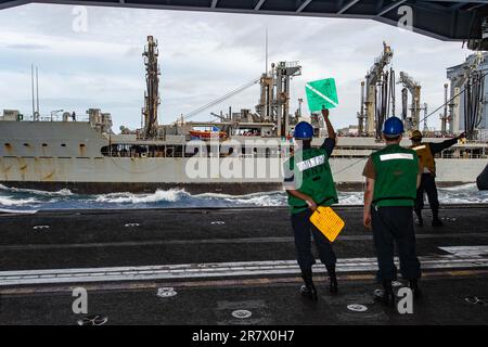 230613-N-PS962-1045 SEELEUTE DER PHILIPPINEN SEE (13. Juni 2023) an Bord der USA Der einzige vorwärtsgesetzte Flugzeugträger der Navy, USS Ronald Reagan (CVN 76), bereitet sich darauf vor, während einer Betankung auf See mit dem Flottenöler USNS Rappahannock (T-AO 204) in der Philippinischen See Vorräte in der Hangarbucht aufzunehmen. Befehlshaber der Task Force 73 (CTF-73) in Abstimmung mit dem militärischen Sealift-Kommando Far East (MSC FE) betankt und liefert entsandte Marinekräfte zusammen mit regionalen Verbündeten und Partnern im Indo-Pazifik nach. Ronald Reagan, das Flaggschiff der Carrier Strike Group 5, ist kampfbereit Stockfoto