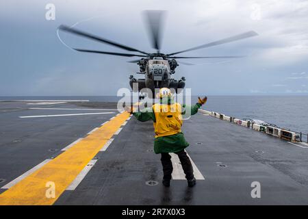 PHILIPPINE SEA (13. Juni 2023) Aviation Boatswain’s Mate (Handling) 3. Class Donald Elliot, aus Kansas City, Missouri, dem nach vorn eingesetzten Amphibienflugzeugträger USS America (LHA 6) zugewiesen, startet einen CH-53E Super-Hallion-Hubschrauber vom 31. Marine Expeditionary Unit (MEU) Air Combat Element (ACE), Vom Cockpit des Schiffes während einer schnellen Seilübung während des Segelns in der Philippinen See, Juni 13. America, das führende Schiff der America Amphibious Ready Group, ist im US-Flottengebiet 7. tätig. U.S. 7. Fleet ist die USA Die größte Zahl vorstationierter Schiffe der Marine Stockfoto