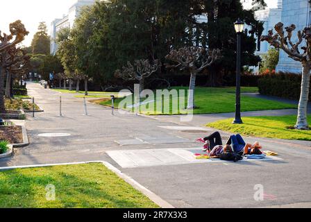 Zwei Studenten legten sich auf einen Fußweg, um den Sonnenuntergang vom Campus der University of California, Berkeley, zu beobachten Stockfoto