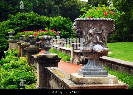 In einem formellen Garten auf einem Grundstück in Long Island halten griechische Urnen hübsche Blumen Stockfoto