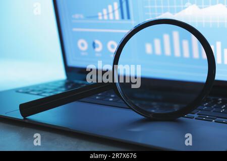 Lupe auf der Tastatur eines Laptops vor hellem Hintergrund, Nahaufnahme Stockfoto