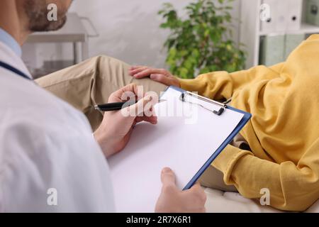 Arzt schreibt Beschwerden von Patienten während der Sprechstunde in der Klinik auf, Nahaufnahme Stockfoto