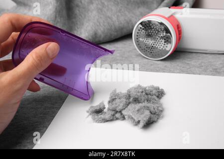 Frau hält Flauschensammler aus Textilrasierer und Fusseln auf hellgrauem Tuch, Nahaufnahme Stockfoto