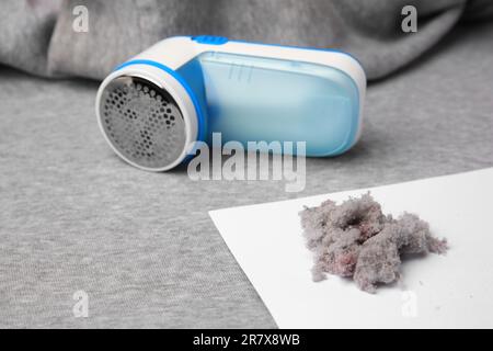 Moderner Rasierer und Fusseln auf hellgrauem Tuch Stockfoto