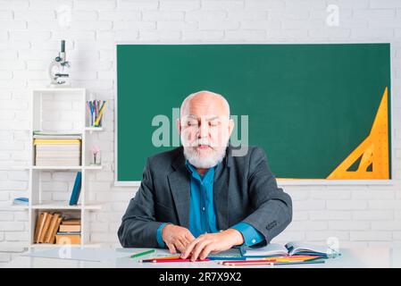 Professor im Klassenzimmer an der Schule. Ein Lehrer, der beruflich arbeitet. Ein Lehrer, der viel weiß. Brillenlehrer. Sehr Geehrter Professor. Senioren Stockfoto