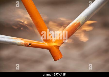 Manuelle Fahrradrenovierungsarbeiten, Lackentfernung durch Brennerfeuer, um die Farbe eines Fahrradrahmens zu ändern. Nahaufnahme. Stockfoto