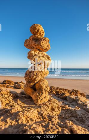 Eine Gruppe von fünf Kalksteinfelsen, die sich an einem leeren Strand übereinander balancieren Stockfoto