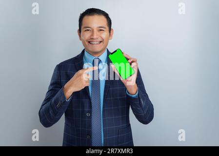 Junger Mexikaner mit brauner Haut als Unternehmer oder Geschäftsmann zeigt auf sein Modell-Handy mit grünem Bildschirm, eine Person Stockfoto