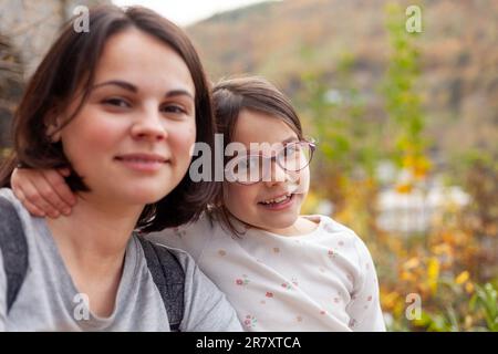 Porträt einer glücklichen Mutter und ihrer Tochter im Herbstpark Stockfoto