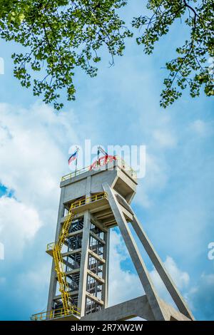 Der Turm des ehemaligen Minenschachts gegen den blauen Himmel und in Begleitung eines Baumes. Derzeit ein Aussichtsturm. Shaft Präsident, Chorzow, Polen Stockfoto