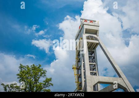 Der Turm des ehemaligen Minenschachts gegen den blauen Himmel und in Begleitung eines Baumes. Derzeit ein Aussichtsturm. Shaft Präsident, Chorzow, Polen Stockfoto