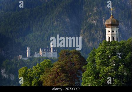 Schwangau, Deutschland. 18. Juni 2023. Schloss Neuschwanstein steht hinter der Wallfahrtskirche St. Kolumaner im Morgenlicht. In einem Referendum am Sonntag sollen die Bewohner Schwangaus entscheiden, ob sie die Nominierung von Neuschwanstein zum Weltkulturerbe unterstützen. Kredit: Karl-Josef Hildenbrand/dpa/Alamy Live News Stockfoto