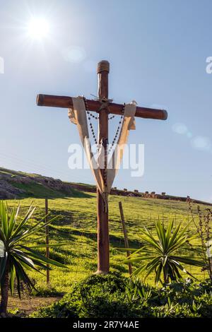 Foto eines hölzernen Kreuzes auf dem Berg, mit einem Rosenkranz, Konzeptreligion Stockfoto