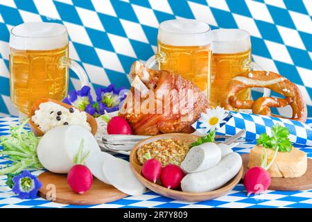 Oktoberfest mit Bier, Haxe, Weisswurst, Radi und Bayerische Flagge blau weiß im Hintergrund Stockfoto