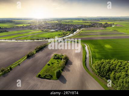 Sonnenuntergang über dem Frühlingsfeld mit Dorf, Slowakei - Blick auf die Drohne Stockfoto