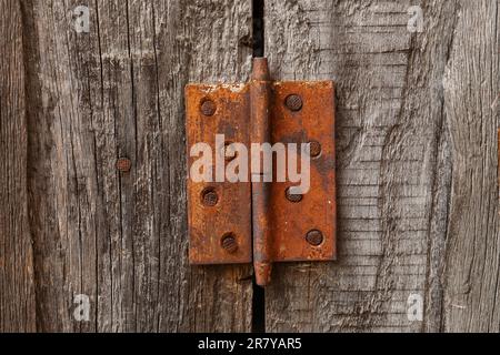 Altes rostiges Scharnier an einer Holztür. Ein alter rustikaler Hintergrund. Stockfoto