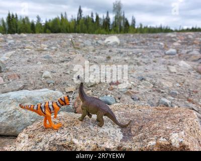 Zwei Spielzeugdinosaurier auf Steinen und Trümmern. Stockfoto