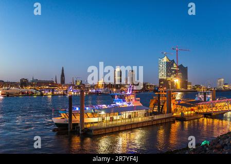 Nachtbild der beleuchteten Skyline von Hamburg an der Elbe mit den Sehenswürdigkeiten der Elbphilharmonie und Teilen der neuen HafenCity. Stockfoto