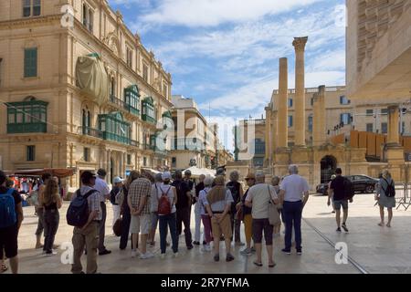 Gruppenreisen halten im Schatten, um den Erläuterungen des Reiseleiters in der Altstadt von Valletta, Malta, zu lauschen Stockfoto