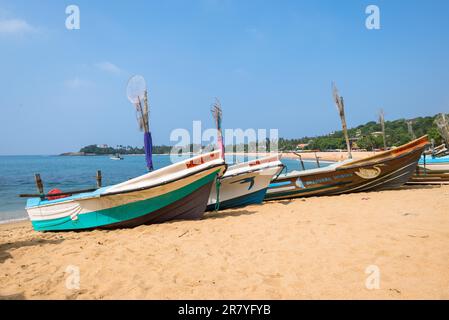 Am Strand einer der wichtigsten Touristenattraktionen im Südwesten Sri Lankas. Outrigger und traditionelle Fischerboote am Strand und vor Anker Stockfoto