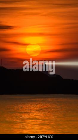 In der Dämmerung ist die Sonne hinter dem Leuchtturm. Das Fugui Cape Lighthouse in Shimen. Taiwan Stockfoto