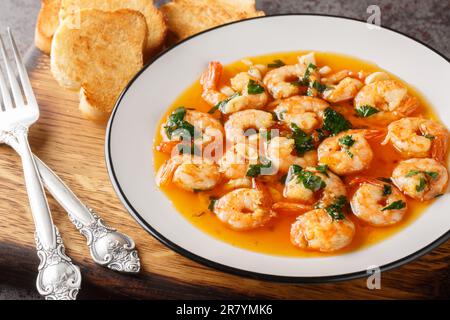 Gambas al Ajillo oder Knoblauchgarnelen sind traditionelle spanische Tapas, die aus einer Kombination aus frischen Garnelen und einer Ajillo-Sauce auf dem Holzbrett hergestellt werden. Horizontal Stockfoto
