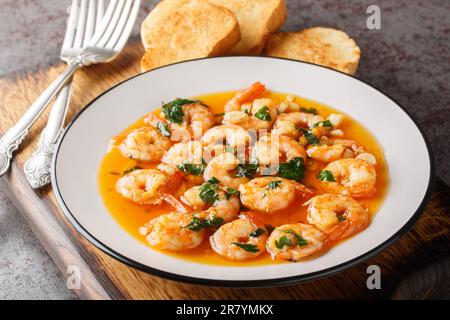 Gebratene Garnelen mit Knoblauch und heißem Paprika in duftendem Olivenöl, Nahaufnahme auf einem Holzbrett auf dem Tisch. Horizontal Stockfoto