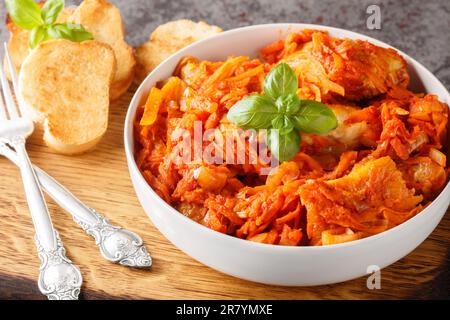 Köstlicher Fischeintopf mit Gemüse in scharfer Tomatensauce, serviert mit Toast, Nahaufnahme auf einem Holzbrett auf dem Tisch. Horizontal Stockfoto