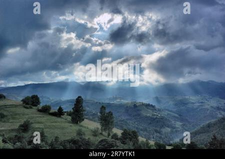 Eine dramatische Landschaft der Karpaten, beleuchtet von einem Sonnenstrahl, der durch einen stürmischen Himmel im Hintergrund scheint Stockfoto