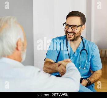 Porträt eines Arztes oder pflegenden Mannes mit einem älteren Mann, der zu Hause oder im Pflegeheim die Hand schüttelt Stockfoto