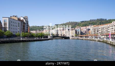 Der Fluss Nervión im Zentrum von Bilbao, mit dem Rathaus im Hintergrund und dem Berg Artxanda dahinter an einem sonnigen Tag. Die größte Stadt im Basqu Stockfoto