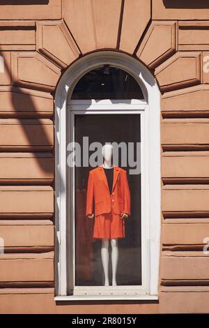 Eine Schaufensterpuppe in Damenbekleidung steht im Fenster eines alten Hauses Stockfoto