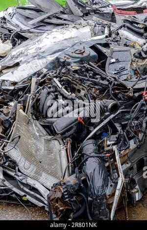 Die Vorderseite eines schwer zerstörten Autos. Fahrzeug völlig zertrümmert, Motor sichtbar, Motorhaube fehlt. Das Auto ist nicht identifizierbar und kaum als Auto zu erkennen. Stockfoto