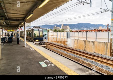 Die Insel-ähnliche Plattform des Bahnhofs Sakura Shukugawa in Nishinomiya, an der JR Kobe-Linie, mit einigen Leuten, die an einem bedeckten Tag warten. Stockfoto