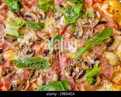 Traditionelle italienische Pizza mit getrockneten Tomaten, Kapern, Prosciutto, Rucola und Mozzarella-Käse isoliert. Stockfoto