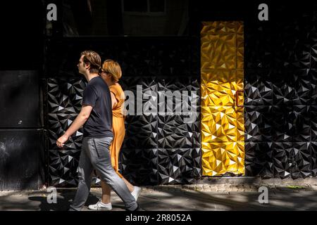 Eine Frau und ein Mann passieren einen schwarz-goldenen Eingang einer Bar am Hohenzollernring, Köln. Eine Frau und ein Mann passieren den schwarz-g Stockfoto